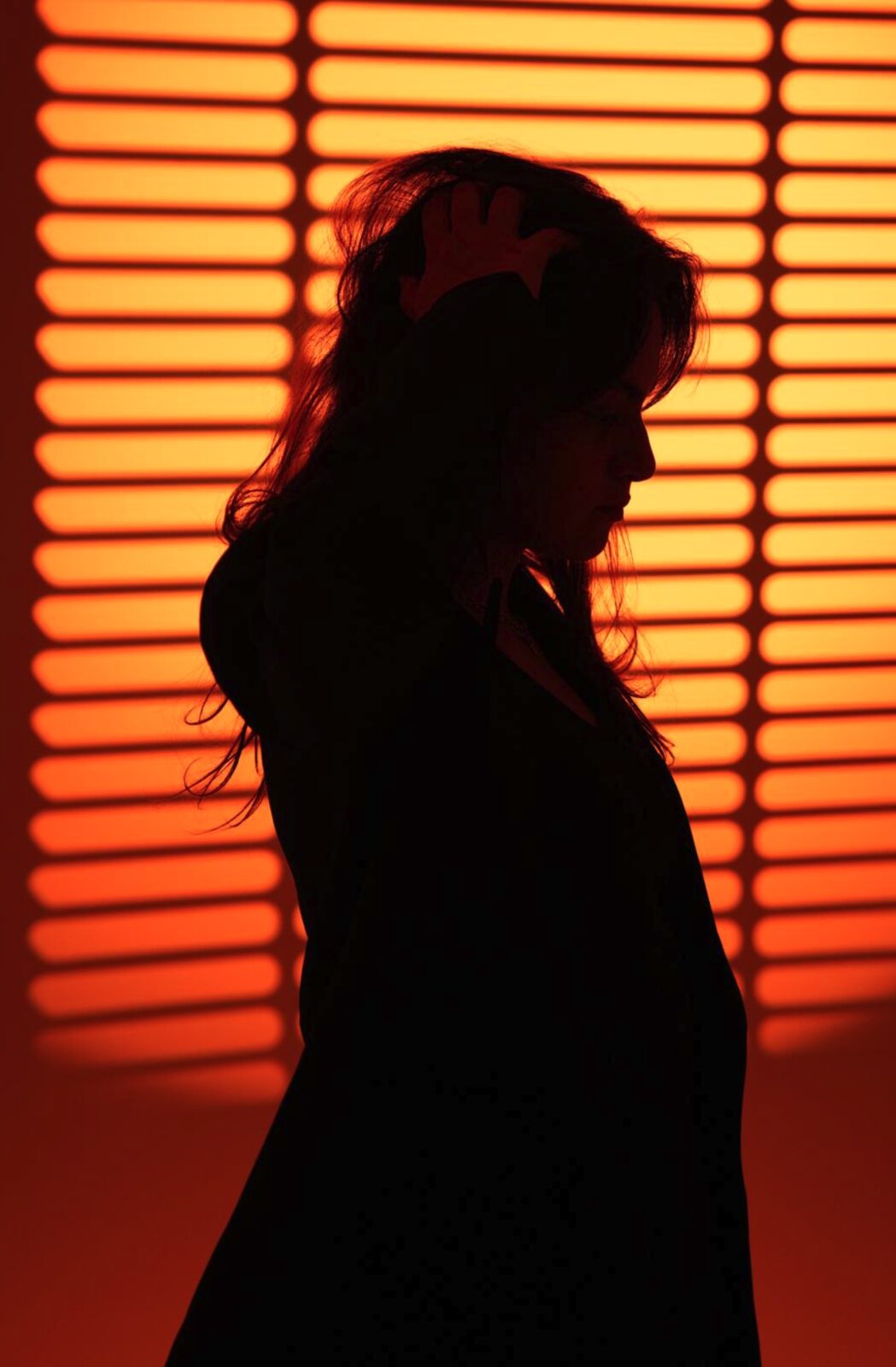 Silhouette against orange louvered light